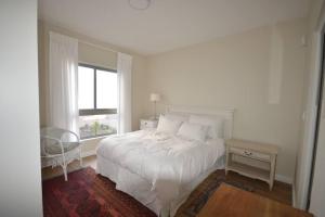 a white bedroom with a bed and a window at Chardon in Langebaan