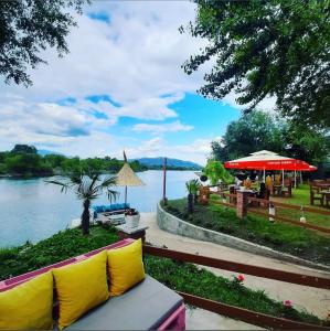 a couch with yellow pillows sitting next to a lake at Villa Teverde in Shkodër