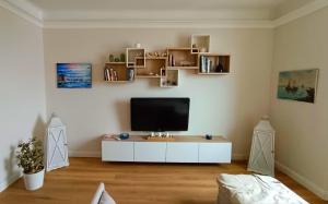 un salon avec une télévision sur un meuble blanc dans l'établissement Mare Monti, à Gênes