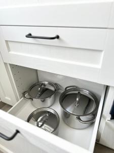 three pots in a drawer in a kitchen at Modernūs apartamentai Šilutėje in Šilutė