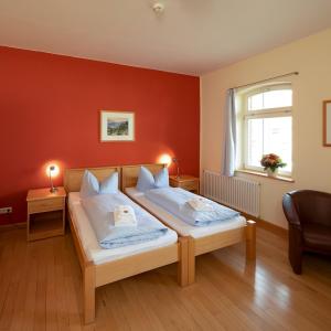 a bedroom with two beds and a red wall at Biohotel Stiftsgut Wilhelmsglücksbrunn in Creuzburg