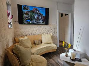 a living room with a couch and a tv on the wall at Gästezimmer Ihr Quartier Erdgeschoss Zimmer 2 in Gontenschwil