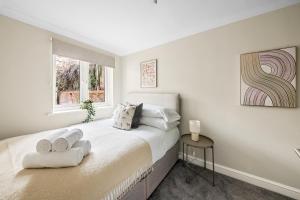 ein weißes Schlafzimmer mit einem Bett mit Handtüchern darauf in der Unterkunft Reading City Centre - Free Parking - Business Stays in Reading