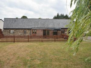 a house with a wooden fence and a yard at 2 Bed in South Molton 62654 in Filleigh