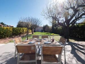 拉特斯的住宿－Villa Horizon - climatisation et jardin，一张带椅子的木桌和一瓶葡萄酒