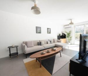 Villa Horizon - climatisation et jardin في لات: غرفة معيشة مع أريكة وطاولة قهوة