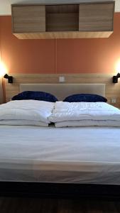 a bed with white sheets and blue pillows at Chalet Trigano in Lauwersoog
