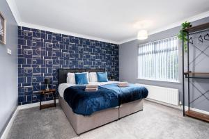 1 dormitorio con cama y pared azul en Stylish House with Garden, en Knottingly