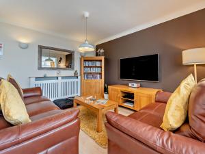 a living room with leather furniture and a flat screen tv at 2 Bed in Saundersfoot 94207 in Saundersfoot
