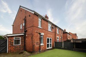 a red brick building with a green yard at Stylish House with Garden in Knottingly