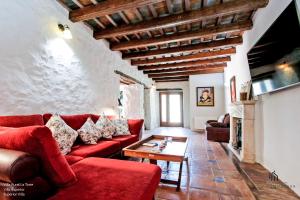 BenadalidにあるLiving4Malaga Villas Rurales Grazalemaのリビングルーム(赤いソファ、テーブル付)