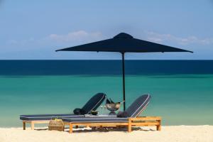 een strand met een parasol en stoelen op het strand bij Avaton Luxury Beach Resort - Relais & Chateaux in Ouranoupoli