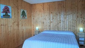 a bedroom with a bed with wooden walls and two lamps at Nette Ferienwohnung in Le Camille mit Großem Garten in San Zeno di Montagna