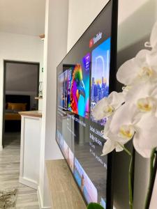 einen Flachbild-TV im Wohnzimmer mit weißen Blumen in der Unterkunft Sobe VaLux Valpovo in Valpovo
