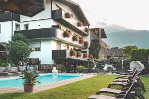 a hotel with a pool and chairs and a building at Hotel Turmwies in Tirolo