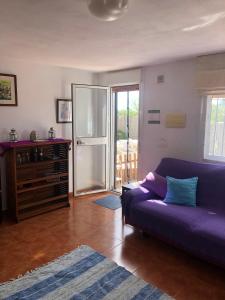 un soggiorno con divano viola e porta scorrevole in vetro di Paraiso Baja a Ríogordo