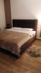 ein großes Bett in einem Schlafzimmer mit Holzboden in der Unterkunft Apartmani MODUS - self service check-in in Virovitica