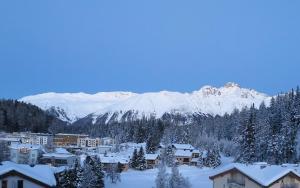 una ciudad cubierta de nieve con montañas en el fondo en Ova Cotschna 705, en St. Moritz