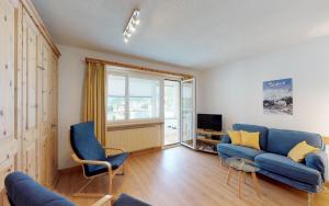 sala de estar con sofá azul y TV en Ova Cotschna 705, en St. Moritz