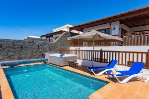 a house with a swimming pool with two chairs and an umbrella at Casa Papillon in Playa Blanca