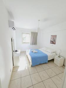 Un dormitorio blanco con una cama azul y una ventana en Stephanie City Apartments, en Lárnaca