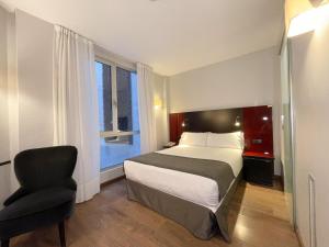 a bedroom with a bed and a chair and a window at SM Hotel Sant Antoni in Barcelona
