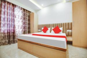a bedroom with a large bed with red pillows at OYO Flagship Dhruva Residency in Shāhpur