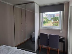 a bedroom with a desk with two chairs and a window at Apartment Tryms vei 20a - Elegant eget bygg in Kristiansand