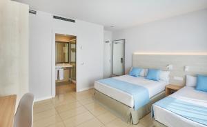 a bedroom with two beds with blue pillows at URH Excelsior in Lloret de Mar