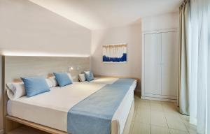a bedroom with a large white bed with blue pillows at URH Excelsior in Lloret de Mar