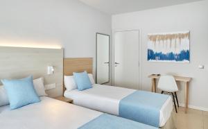 a hotel room with two beds and a desk at URH Excelsior in Lloret de Mar
