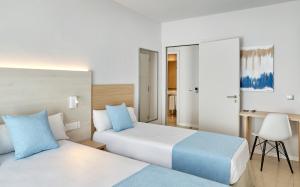 a hotel room with two beds and a desk at URH Excelsior in Lloret de Mar