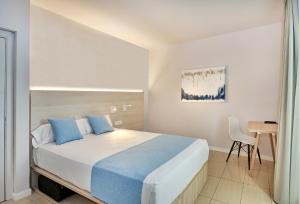 a bedroom with a bed with blue pillows and a desk at URH Excelsior in Lloret de Mar
