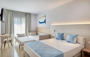 a hotel room with a large bed and a chair at URH Excelsior in Lloret de Mar