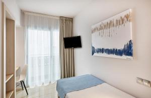 a white room with a bed and a window at URH Excelsior in Lloret de Mar