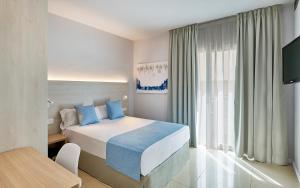 a bedroom with a bed with blue pillows and a table at URH Excelsior in Lloret de Mar