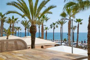 a table with palm trees and the ocean in the background at URH Excelsior in Lloret de Mar