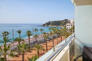 a balcony with a view of the ocean and palm trees at URH Excelsior in Lloret de Mar