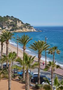 a view of a beach with palm trees and the ocean at URH Excelsior in Lloret de Mar
