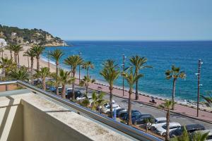 a view of a beach and palm trees and the ocean at URH Excelsior in Lloret de Mar