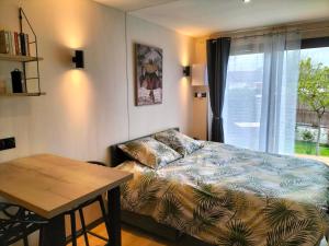 a bedroom with a bed and a table and a window at Studio Zen et Bois in Écouflant