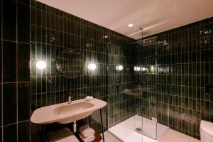 a black tiled bathroom with a sink and a shower at Laceby Manor - Spa & Golf Resort in Laceby
