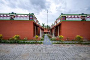 a red brick building with a road in front of it at CHETTINAD HERITAGE WELLNESS RESORTS in Mithilaipatti