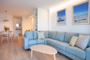 a living room with a blue couch and a table at Apartaments Edificio Puerto in Colònia de Sant Jordi