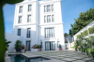 a white building with a pool in front of it at L'Hôtel Particulier La Marsa in La Marsa