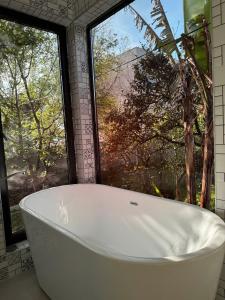 a bath tub in a bathroom with a large window at Orion Cottage in Batumi