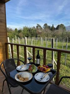 Orion Cottage في باتومي: طاولة مع طبقين من الطعام وزجاجة من النبيذ