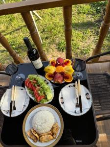 Orion Cottage في باتومي: طاولة مع أطباق من الطعام وزجاجة من النبيذ