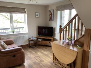 uma sala de estar com um sofá e uma televisão em Byre Cottage em Alston
