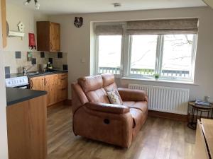 a living room with a leather chair in a kitchen at Byre Cottage in Alston +4 photos